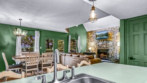 A kitchen with a large island, a dining area with wooden furniture, and a stone fireplace. - Smoky Mountain Bliss 2 Bedroom Cabin (Gatlinburg)