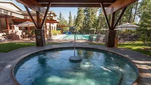A circular hot tub with a central fountain, surrounded by stone tiles and wooden pergolas. - Indian Hills 6021 2 Bedroom Townhouse (Truckee)