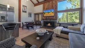 A spacious living room with a fireplace, a dining area, and a kitchen with a refrigerator. - Indian Hills 6021 2 Bedroom Townhouse (Truckee)