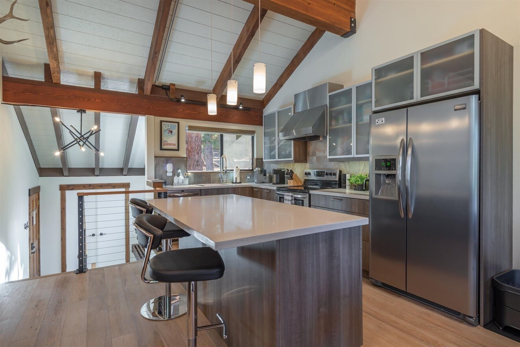 A modern kitchen with a central island, stainless steel appliances, and a wooden ceiling.
