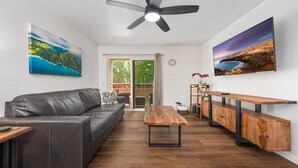 A modern living room with a leather sofa, wooden coffee table, and a wooden bench with drawers. - Big Island Fairway Terrace I-208 1 Bedroom Condo (Waikoloa)