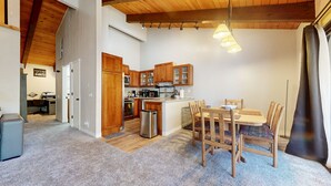 Een compacte keuken met houten kastjes, een centraal eiland en een eethoek met stoelen.