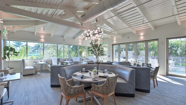 Een moderne lounge met een ronde tafel, comfortabele zittingen en grote ramen met uitzicht op het omliggende landschap.