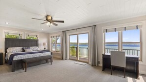 Una camera da letto con un letto, una scrivania e un balcone con vista sull'acqua.