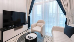 Una sala de estar moderna con un televisor de pantalla plana, un sofá, un sillón y una mesa de centro.
