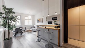 A modern kitchen with a central island, bar stools, and pendant lighting. - RentPlanet - Apartament Święty Marcin (Poznań)