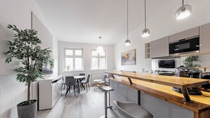 A modern kitchen with a wooden island, bar stools, and a dining area with a table and chairs. - RentPlanet - Apartament Święty Marcin (Poznań)