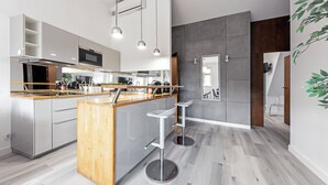 A modern kitchen with a central island, stainless steel appliances, and a grey-tiled backsplash. - RentPlanet - Apartament Święty Marcin (Poznań)