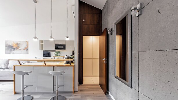 A modern kitchen with a central island, pendant lights, and a view into the dining area. - RentPlanet - Apartament Święty Marcin (Poznań)