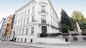 A white building with multiple windows and a corner entrance. - RentPlanet - Apartament Święty Marcin (Poznań)
