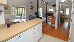 Een moderne keuken met een groot schiereiland, houten vloeren en een eethoek met stoelen en een tafel.