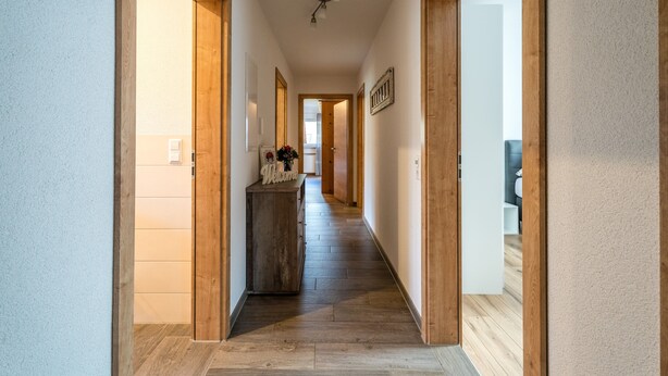 A hallway with wooden flooring, a welcome sign, and a mirror on the wall. - Apartment 'Wiedergrün' with Balcony and Wi-Fi (Durbach)
