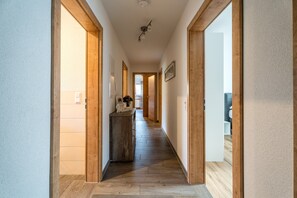 Un couloir doté d’un plancher en bois, d’une pancarte de bienvenue et d’un miroir au mur.