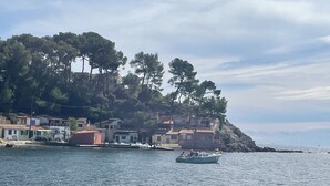 Ein Küstdorf mit Häusern an einem Hügel, einem ruhigen Meer und einem kleinen Boot.