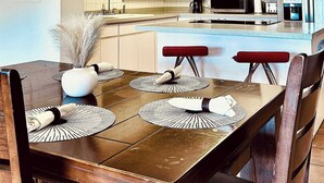 Eine moderne Küche mit weißen Schränken, einem Edelstahl-Kühlschrank und einem Essbereich mit einem Holztisch und Stühlen.
