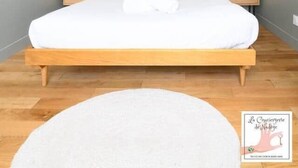 Een moderne slaapkamer met een houten bed, witte beddengoed en een groot raam.