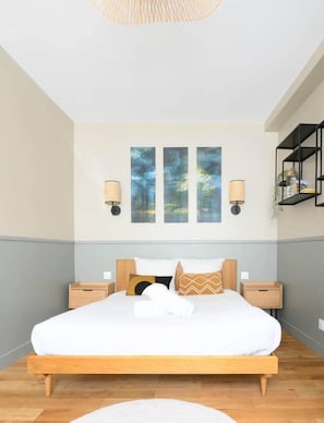 A modern bedroom with a wooden bed, white bedding, and a large window.