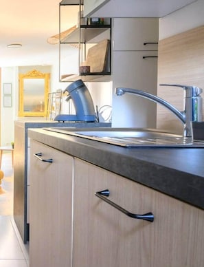 A modern kitchen with a stainless steel sink, wooden cabinets, and a built-in oven.
