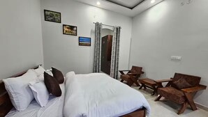 Un dormitorio con una cama, una silla de madera, una mesita y un armario.