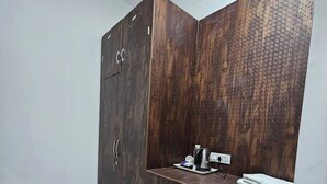 Una habitación con un armario grande, una encimera con una tetera y un plato, y suelo de baldosas.
