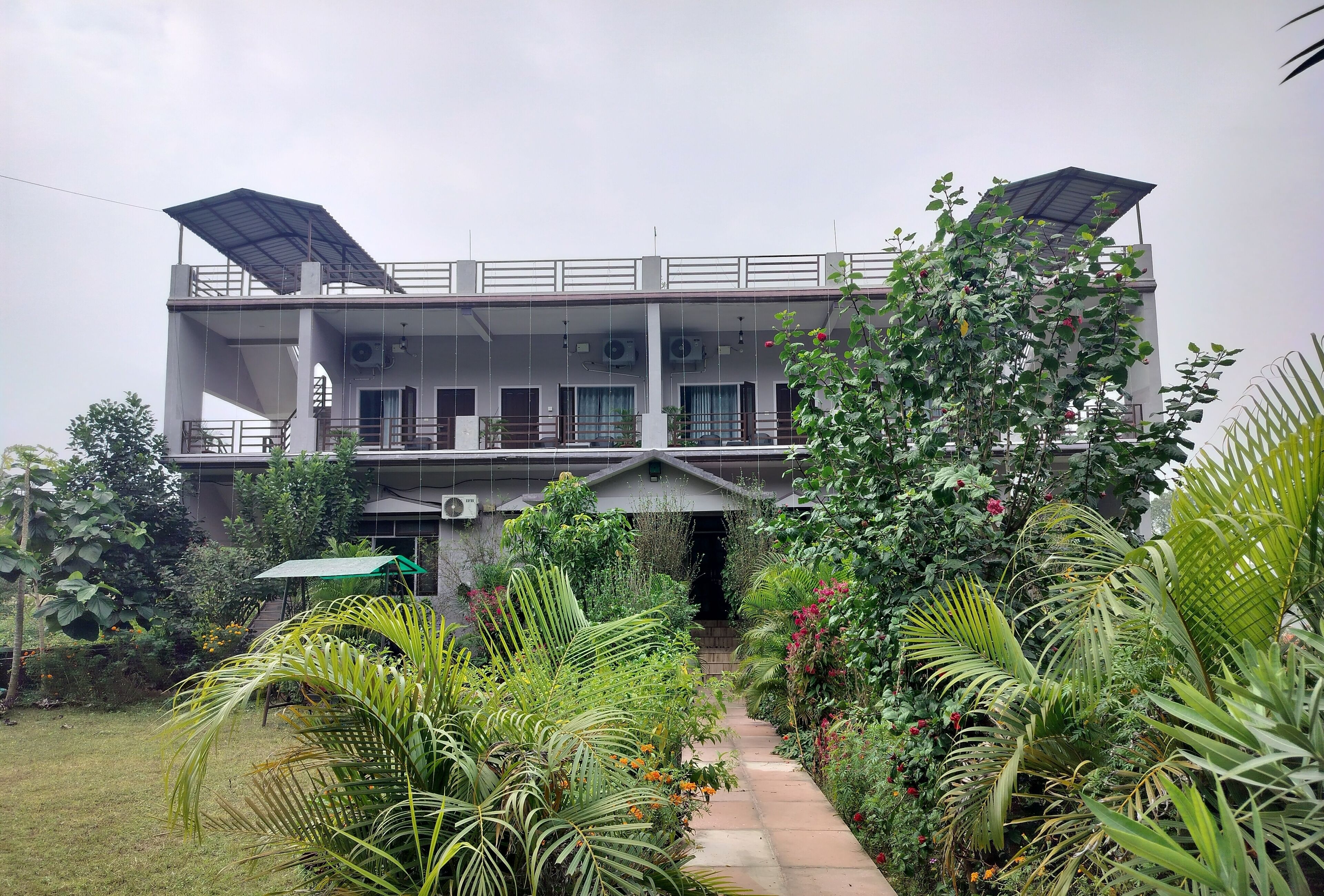 A two-story building with a covered walkway and lush greenery.