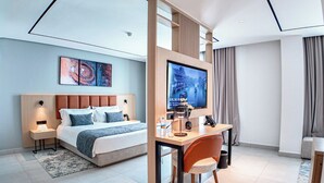A modern hotel room with a large bed, a desk, and a TV.