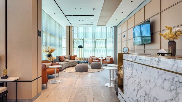 A modern reception area with a marble counter, comfortable seating, and a large TV screen.