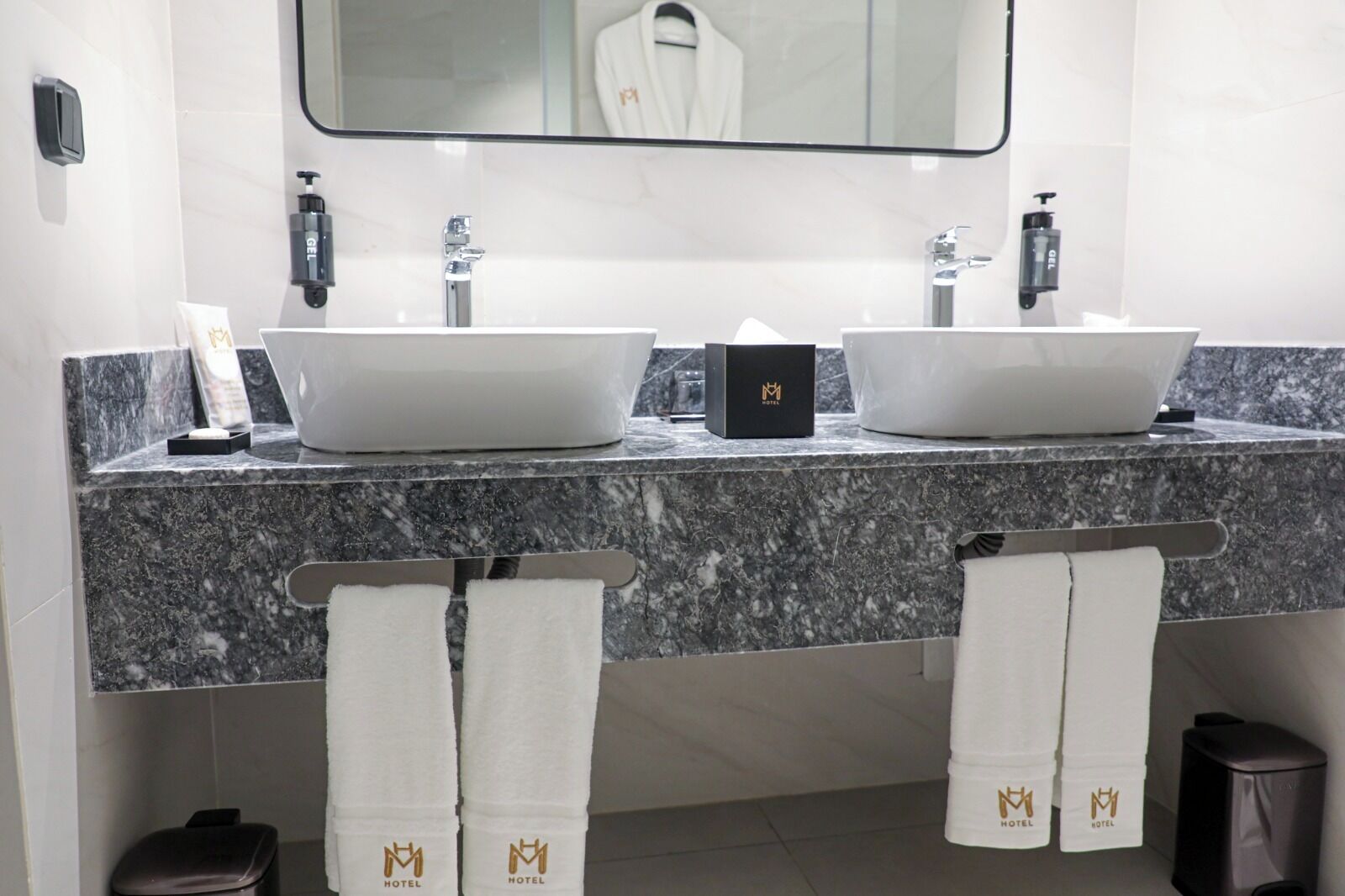 Un baño moderno con dos lavamanos, un espejo grande y un perchero con toallas.