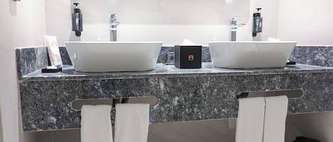 Un baño moderno con dos lavamanos, un espejo grande y un perchero con toallas.