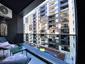 Eine moderne Wohnung mit großem Balkon, Blick auf angrenzende Gebäude und einem kleinen Poolbereich.