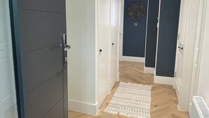 Ein Flur mit einem gemusterten Teppich, einer dunkelblauen Tür und einer weißen Tür.