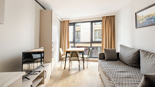Een moderne woonkamer met een bank, televisie, eettafel en stoelen.