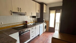 Une cuisine avec des meubles blancs, un four encastré, un évier et un lave-linge.