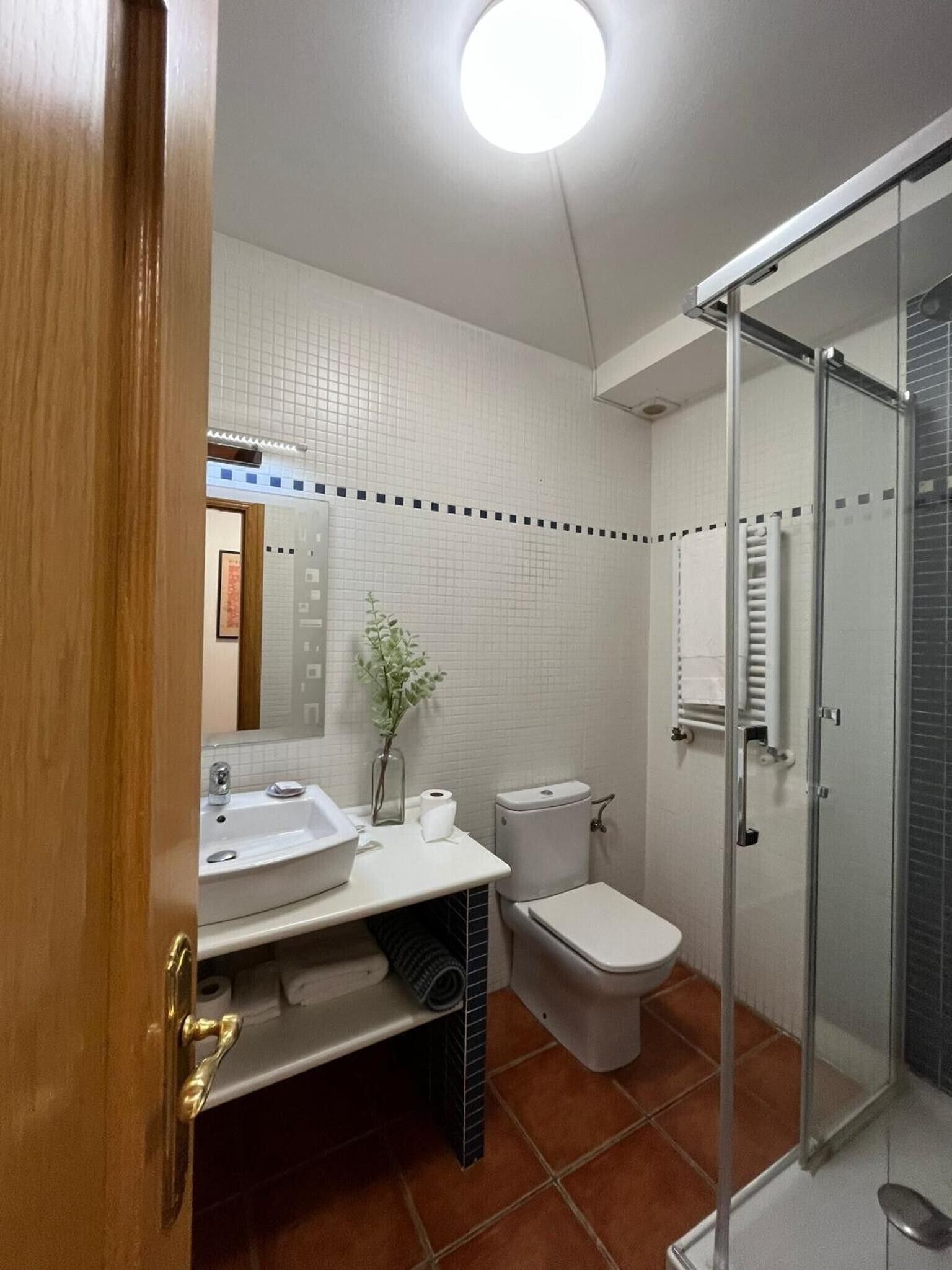 Un baño con lavamanos, inodoro y ducha blancos.