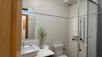 Un baño con lavamanos, inodoro y ducha blancos.