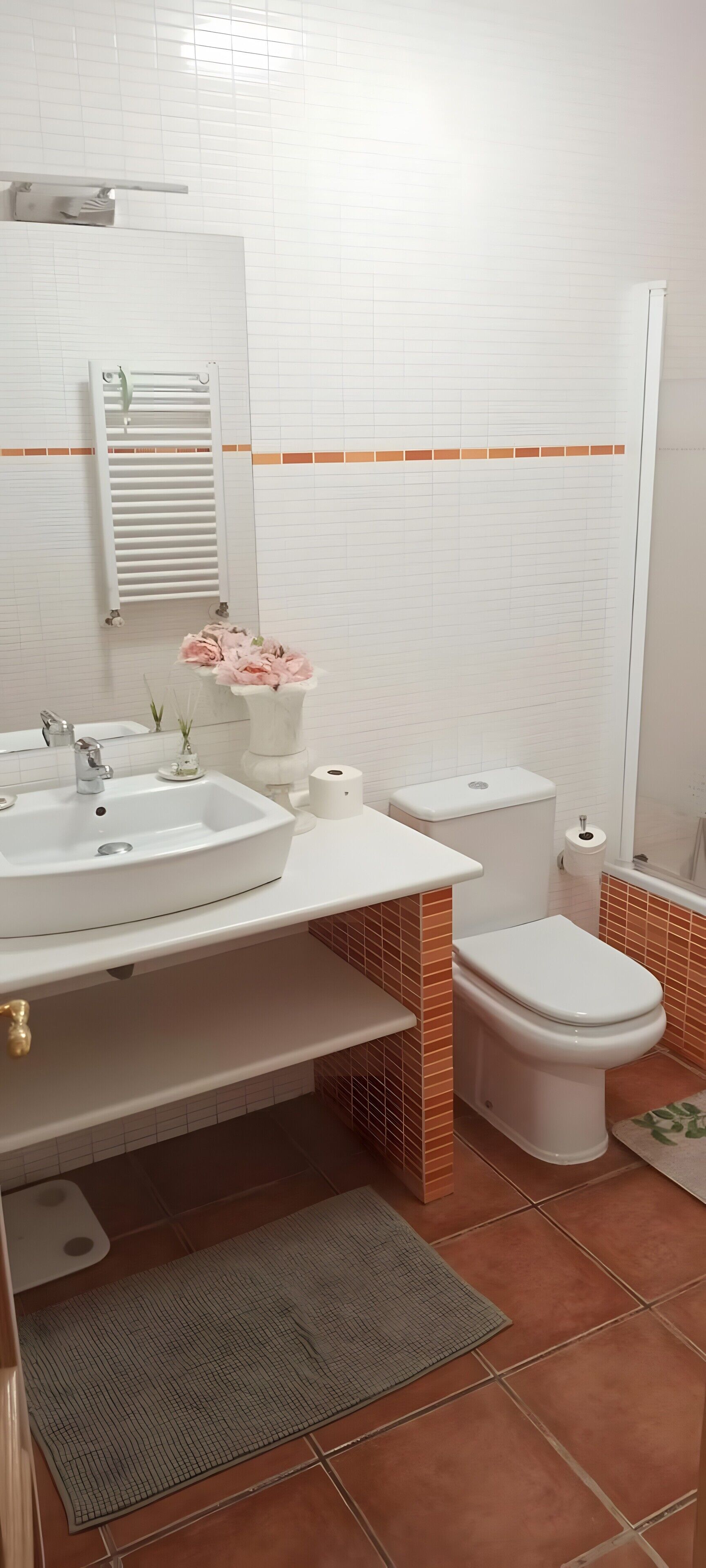 Un baño con lavamanos, inodoro y perchero para toallas.