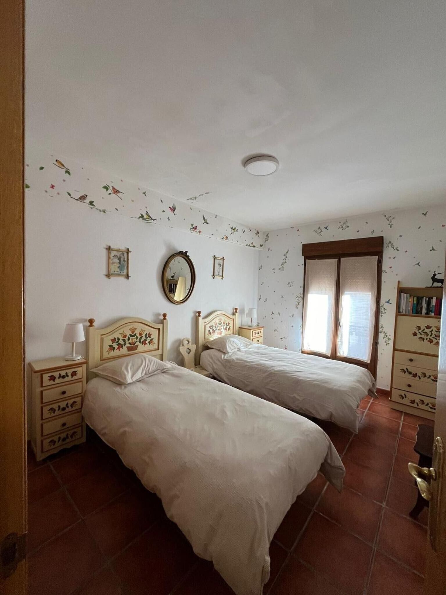 Un dormitorio con dos camas, un aparador, un espejo y una ventana con cortinas.