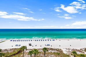 Una playa de arena blanca, agua turquesa cristalina y una hilera de sombrillas azules.