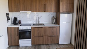 Eine moderne Küche mit Holzausstattung, einer weißen Arbeitsplatte, einem Herd, einem Backofen, einer Spüle und einem Kühlschrank.