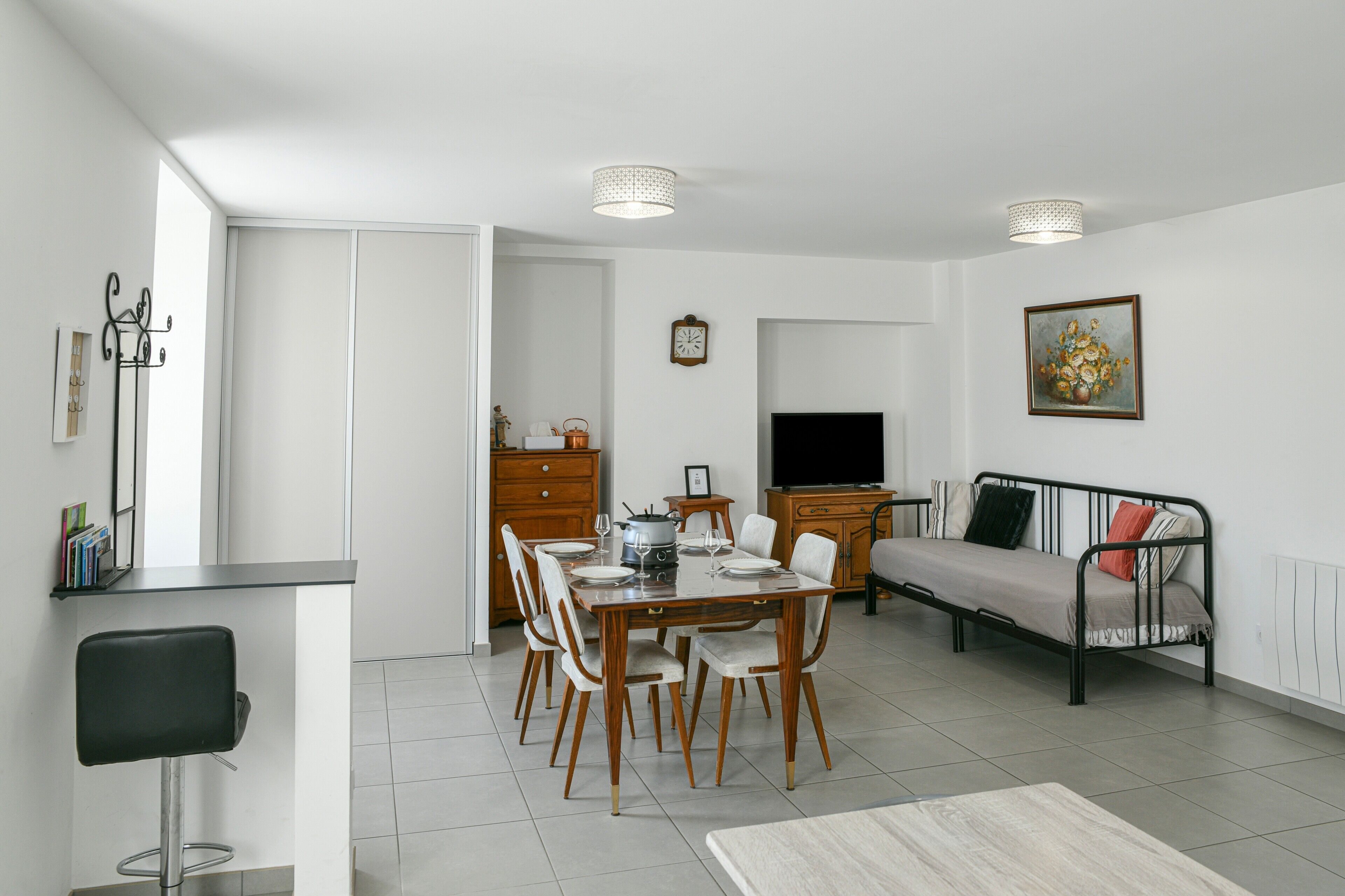Un salon moderne comprenant un coin repas, un canapé, un téléviseur et un tableau accroché au mur.