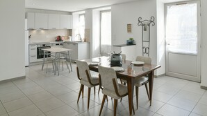 Une cuisine moderne avec des meubles blancs, une table à manger avec des chaises et une grande fenêtre.