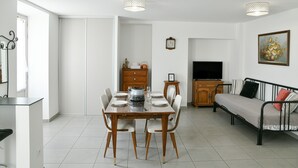 Un coin repas avec une table dressée pour quatre personnes, un canapé, un téléviseur et un meuble.