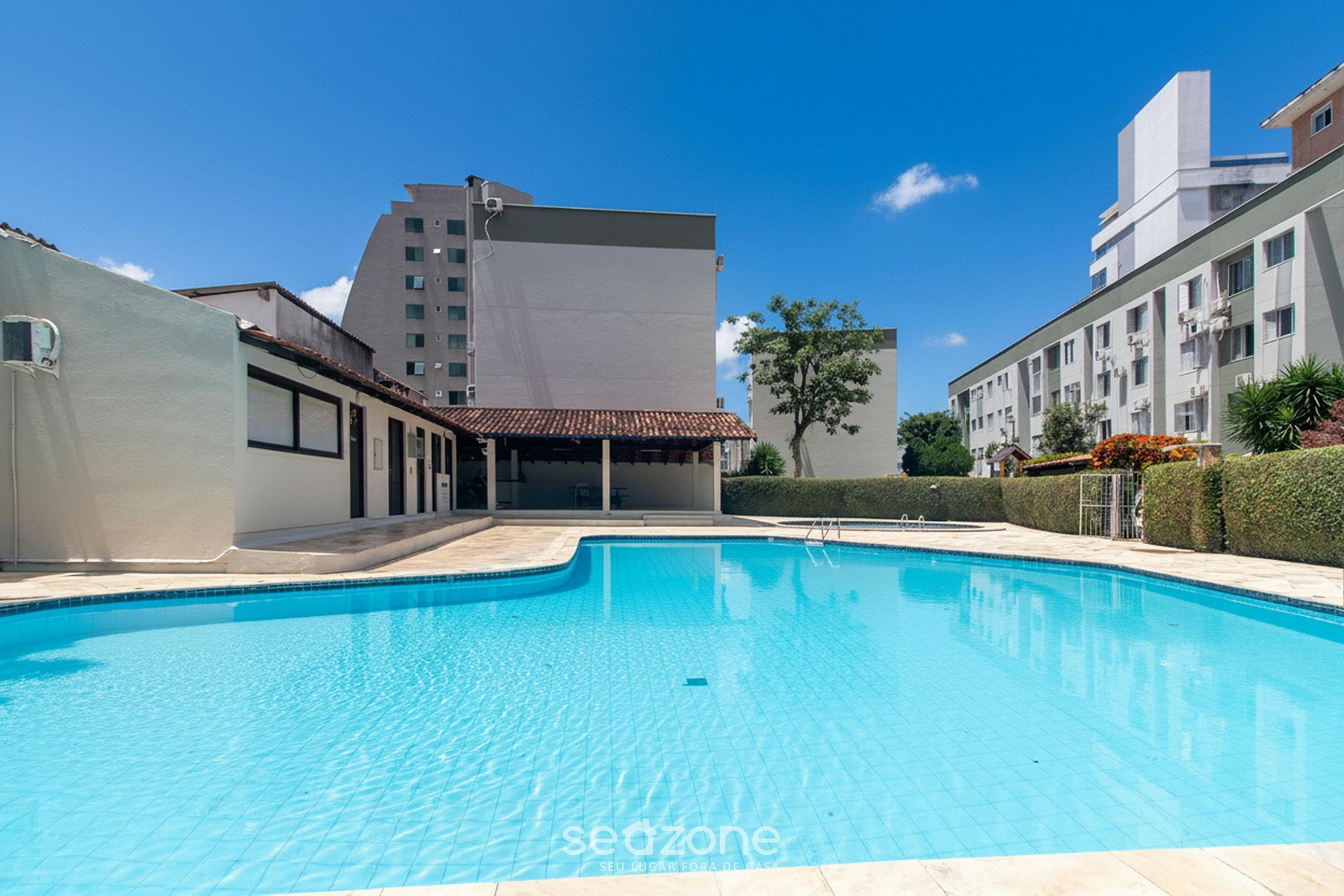 Una piscina rodeada de edificios, con un cielo despejado.