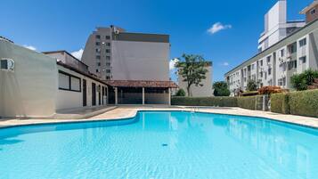 Una piscina rodeada de edificios, con un cielo despejado.