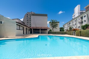 A swimming pool surrounded by buildings, with a clear sky above. - Apt 650 m From Masc in Floripa Bas0401 (Florianópolis)