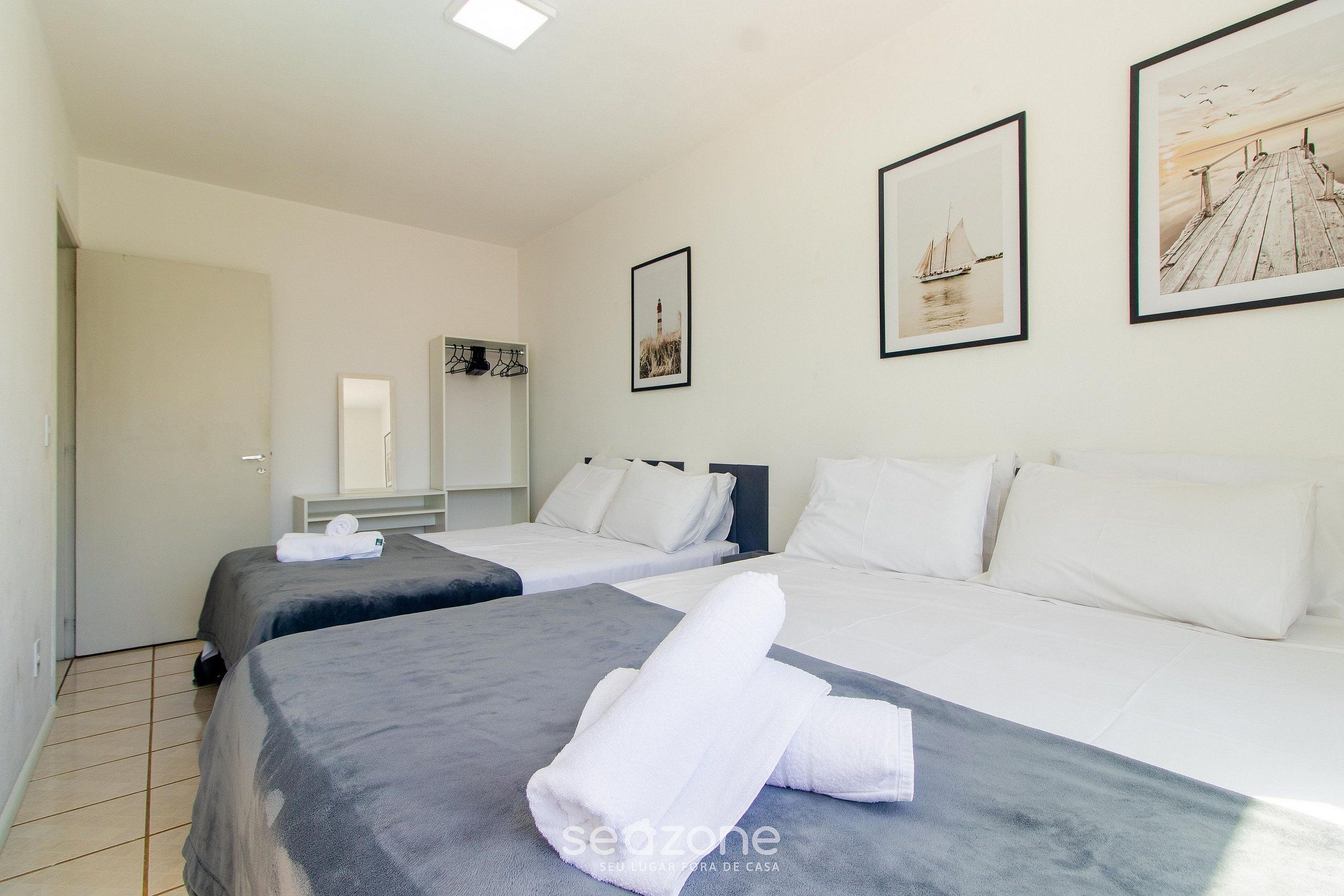 Habitación de hotel con dos camas, ropa de cama blanca y obras de arte en las paredes.