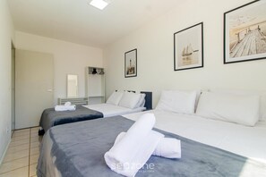 Une chambre d’hôtel avec deux lits, du linge de lit blanc et des œuvres d’art accrochées aux murs.