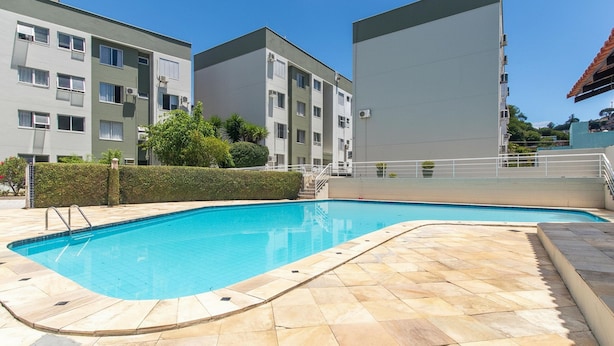 A swimming pool with tiled flooring, surrounded by apartment buildings. - Apt 650 m From Masc in Floripa Bas0401 (Florianópolis)