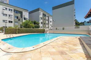 Una piscina con suelo de baldosas, rodeada de edificios de apartamentos.