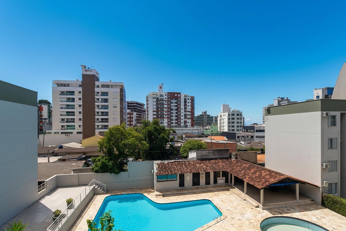 A residential area with a swimming pool, surrounded by modern buildings and a clear blue sky.
